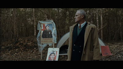 a man standing next to a tent in the woods