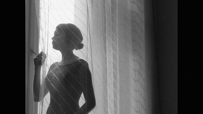 a woman standing in front of a window next to a curtain