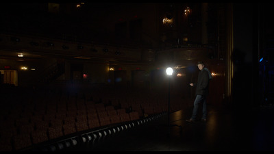 a man standing in front of a microphone in a dark room