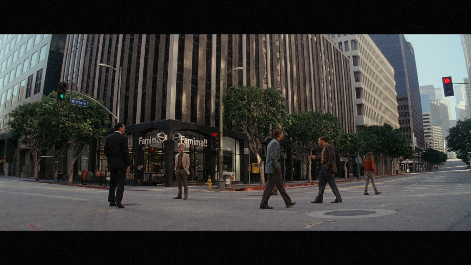 a group of people walking across a street next to tall buildings