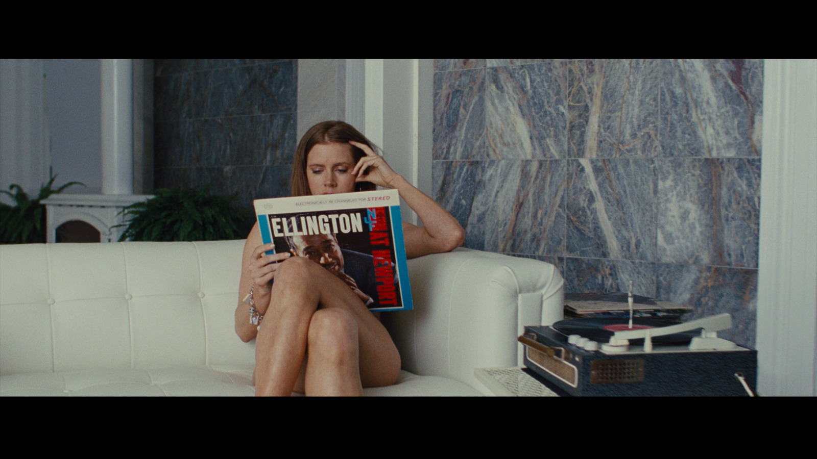 a woman sitting on a couch while reading a magazine