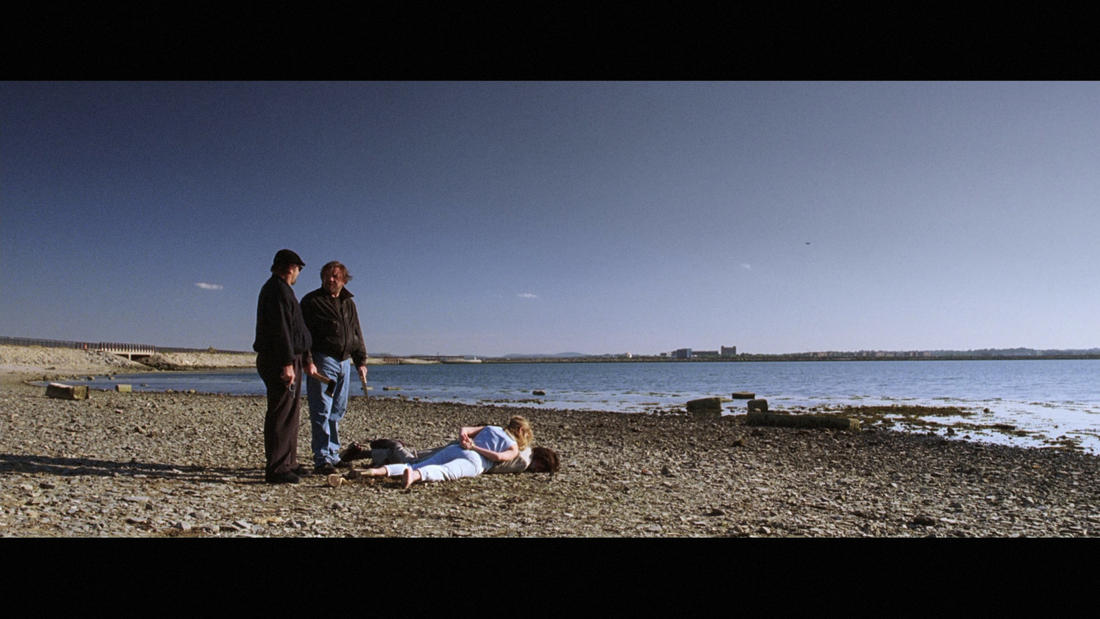 a group of people standing on a beach next to a body of water