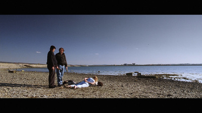 a group of people standing on a beach next to a body of water