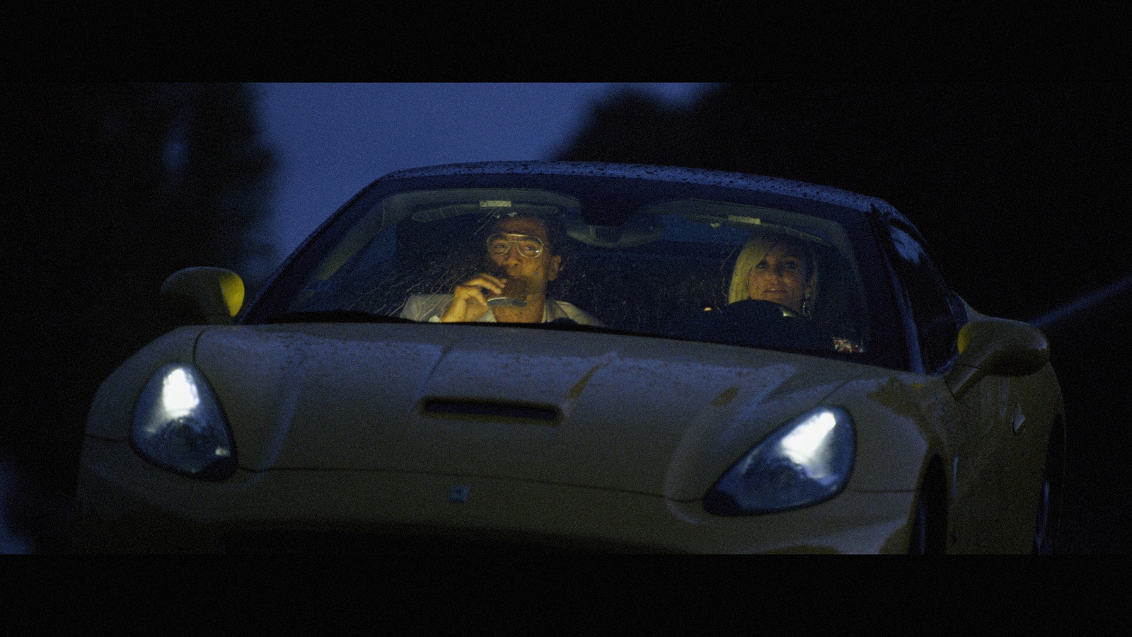 two people sitting in a sports car in the dark