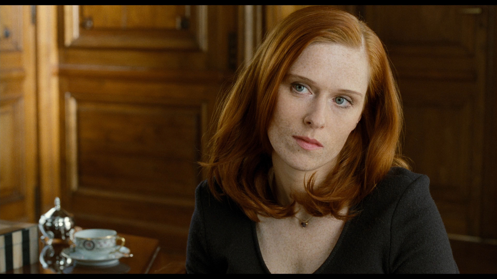 a woman sitting at a table with a cup of coffee