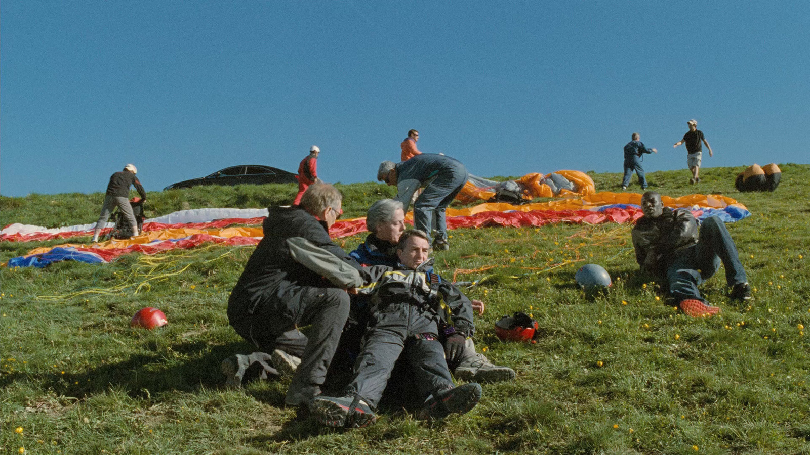 a group of men sitting on top of a lush green field