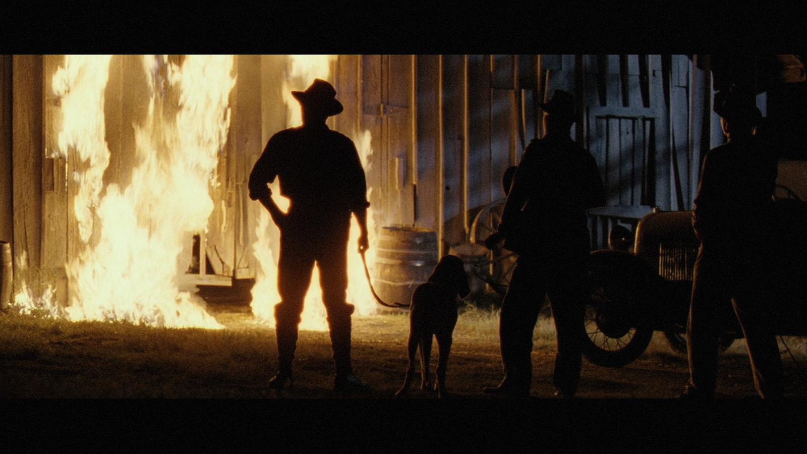 a man standing next to a dog in front of a fire