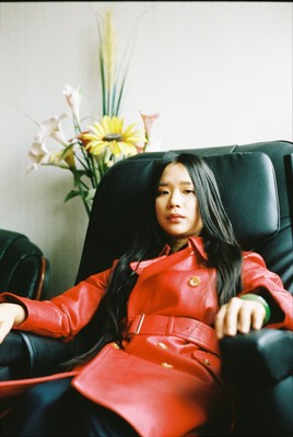 a woman in a red coat sitting in a black chair