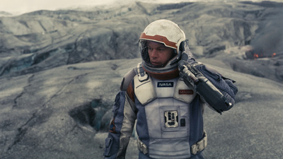 a man in a space suit standing on a mountain