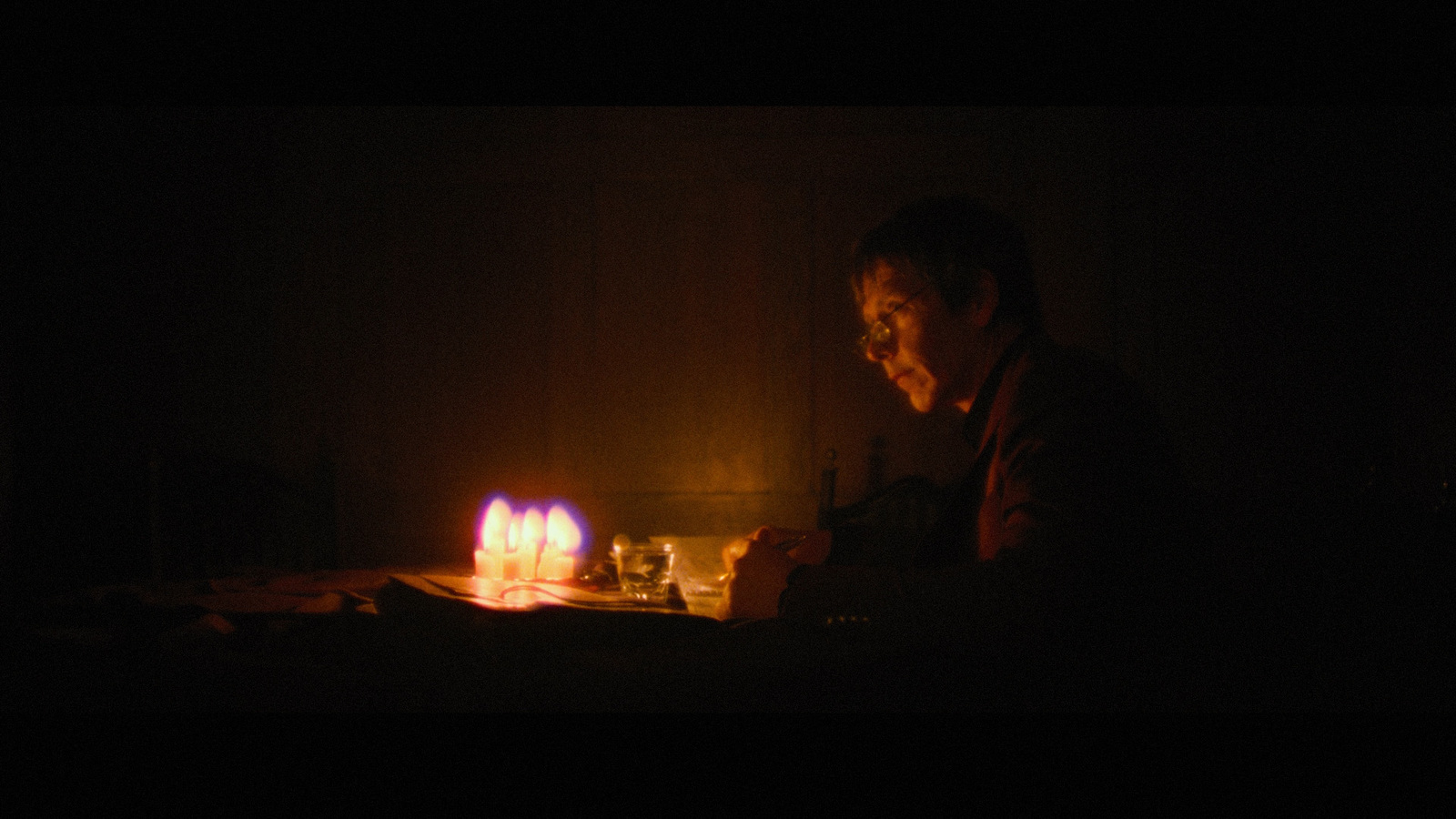 a person sitting in front of a lit candle