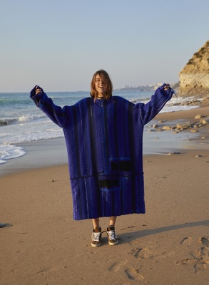 a woman standing on a beach with her arms in the air
