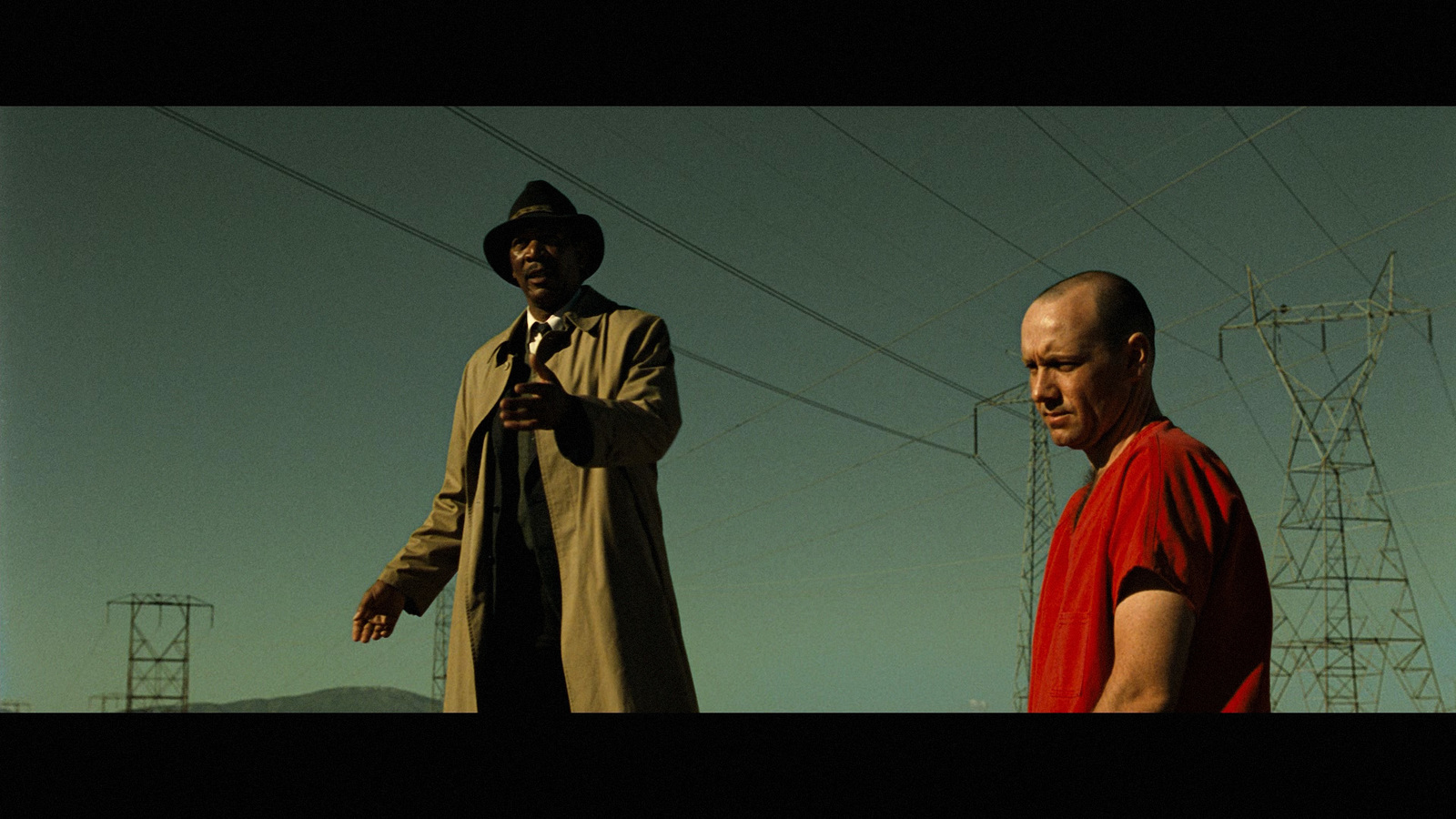 two men standing next to each other in front of power lines