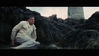 a man sitting on a rock next to a lighthouse