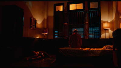 a man standing in a dark room next to a bed