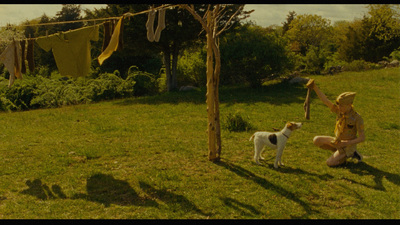 a woman kneeling down next to a dog on a lush green field