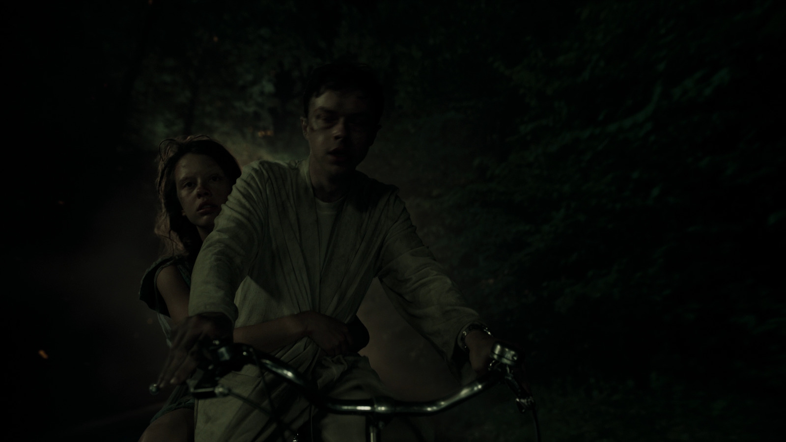 a man and a woman riding a bike in the dark