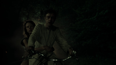 a man and a woman riding a bike in the dark