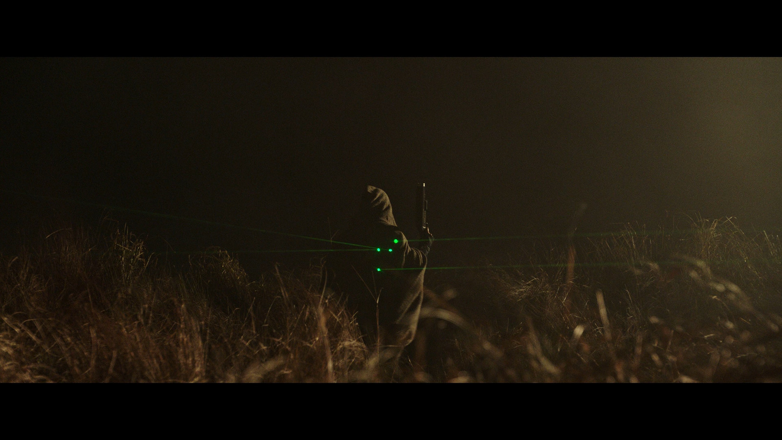 a man standing in a field holding a green light