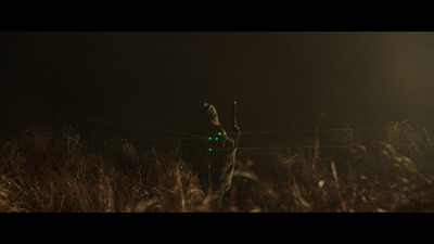 a man standing in a field holding a green light