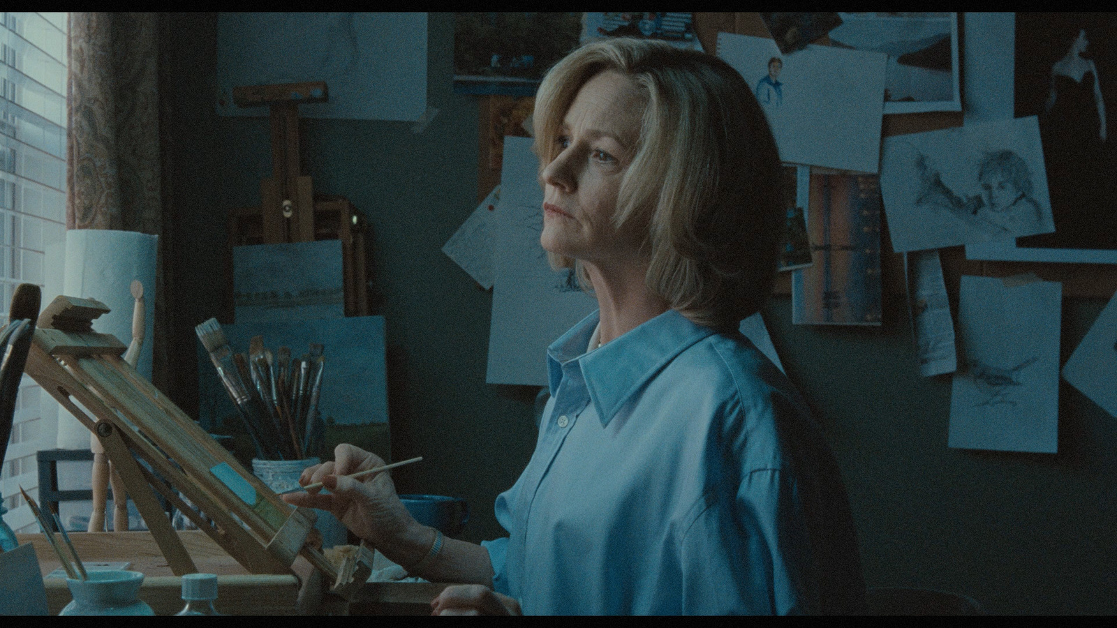 a woman in a blue shirt is holding a paintbrush