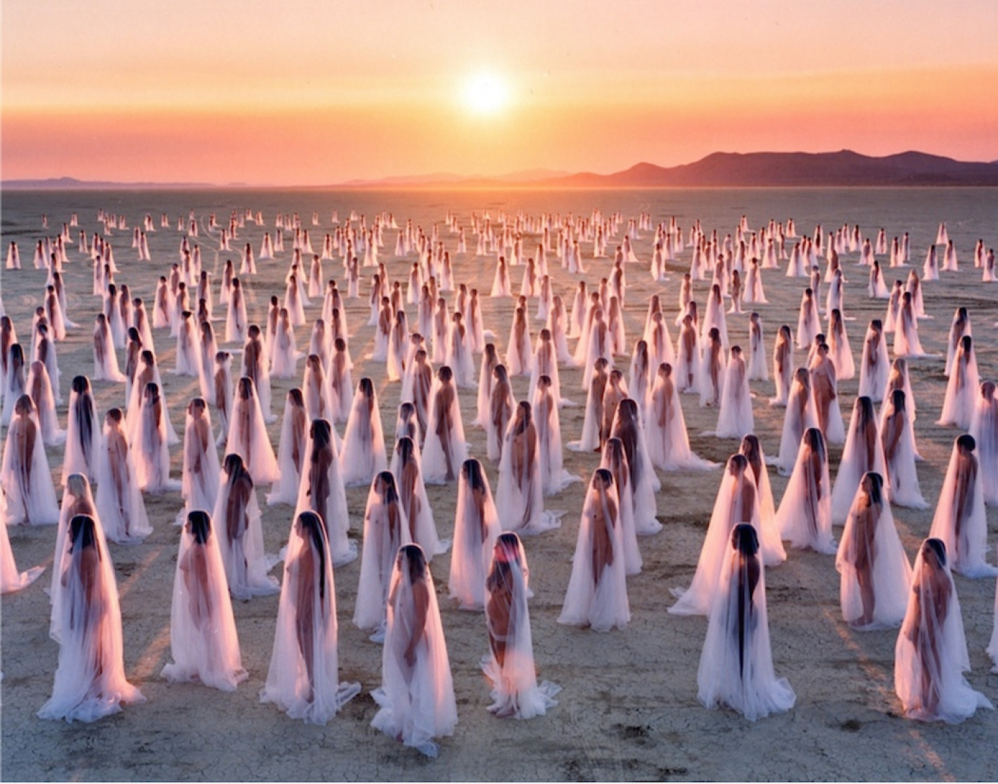 a large group of women standing in the middle of a desert