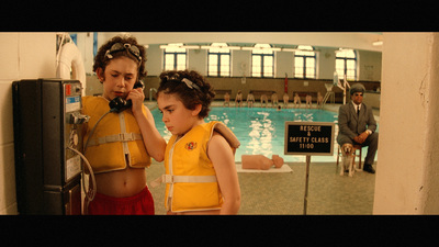 a couple of kids standing next to each other near a swimming pool