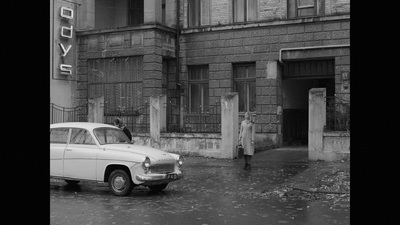 a black and white photo of an old car parked in front of a building