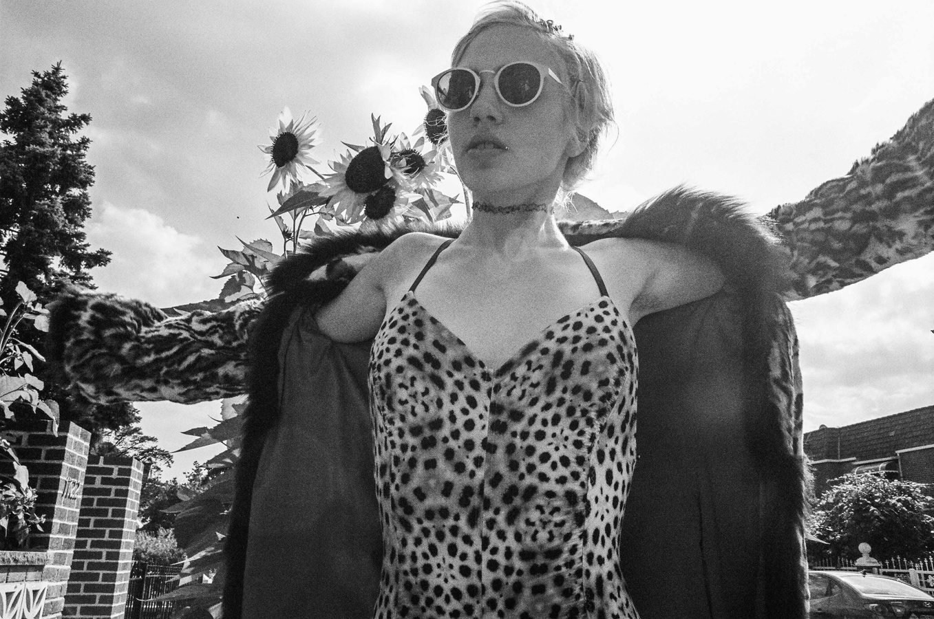 a woman in a leopard print dress and sunflowers