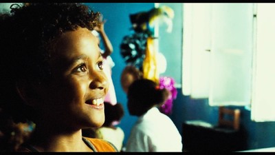 a young boy smiling in a room with other children