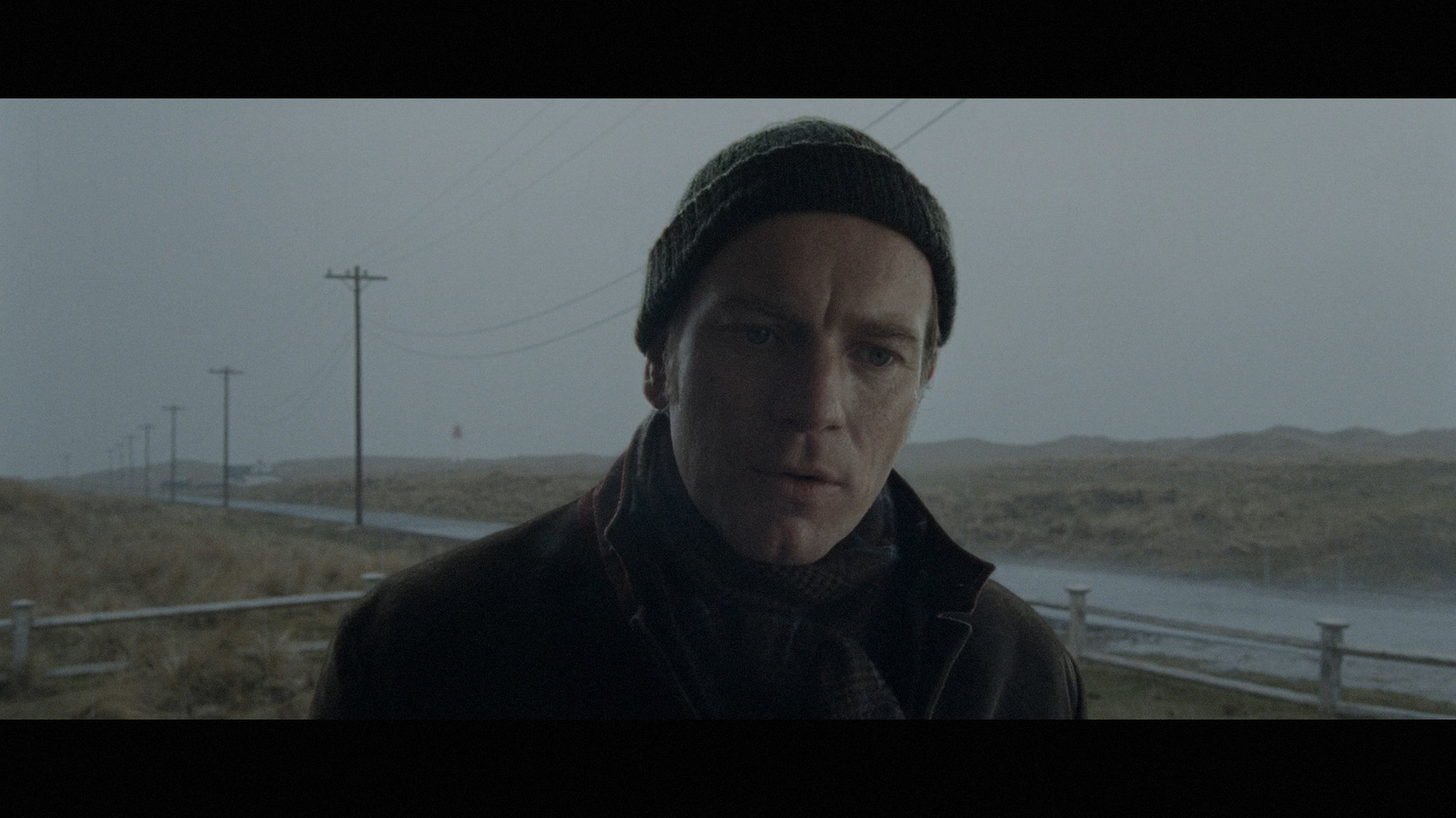 a man standing in front of a fence on a foggy day