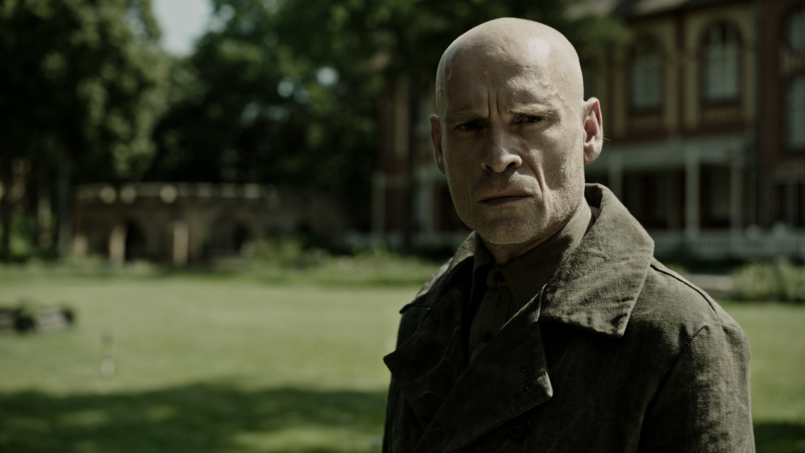 a bald man standing in front of a house