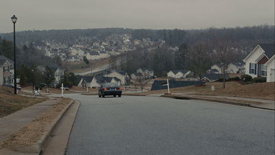 a black car driving down a street next to houses