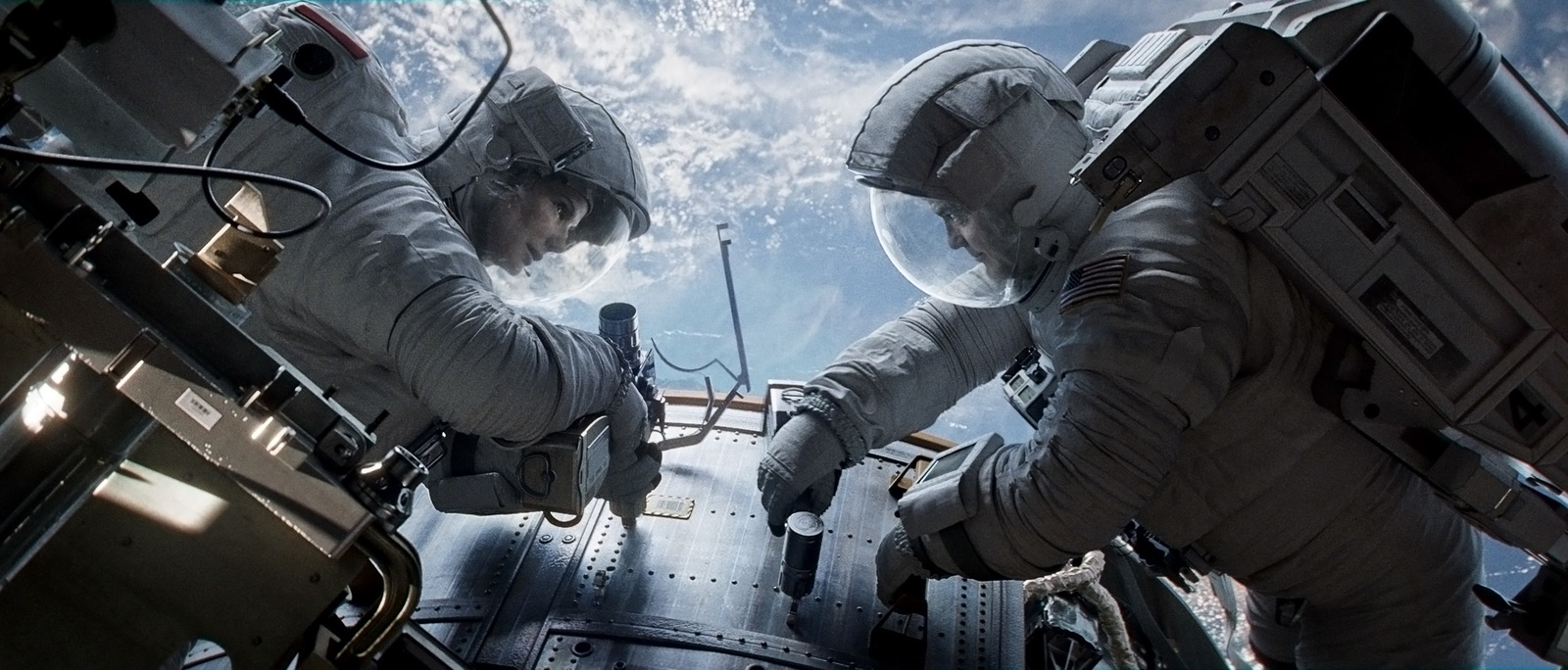 two men in space suits standing inside of a space station