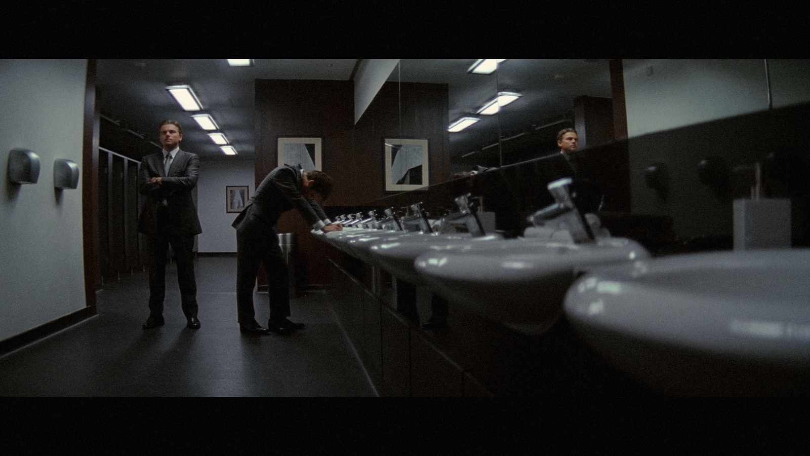 a couple of men standing in a bathroom next to sinks