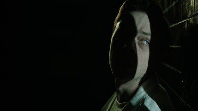 a man in a hoodie looking at something in the dark