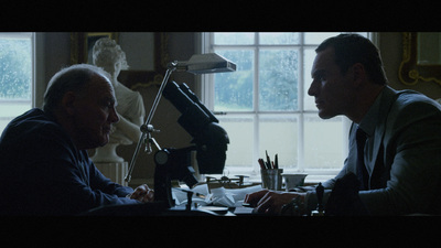 two men sitting at a desk in front of a window