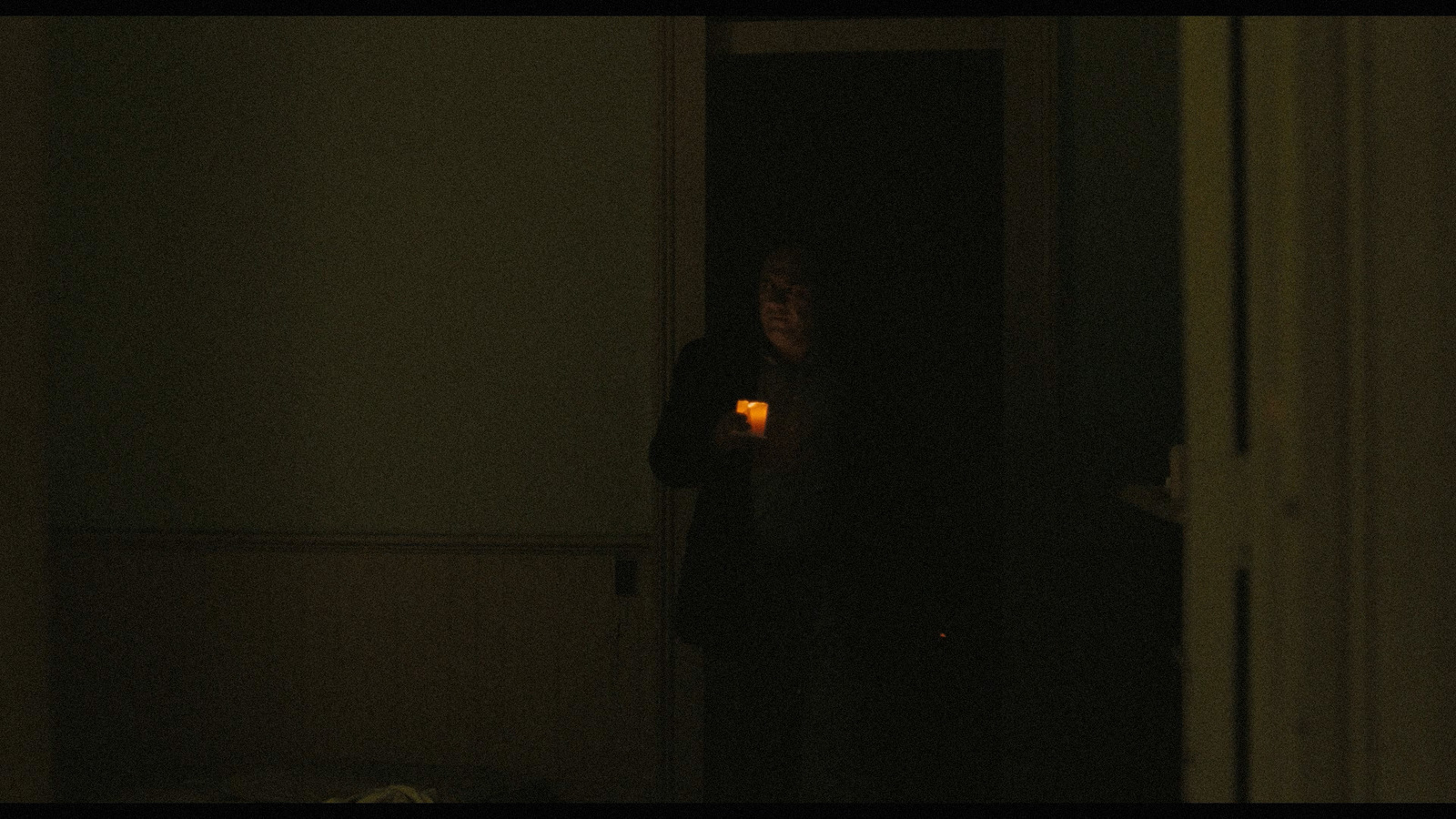 a person standing in a dark room holding a lit candle