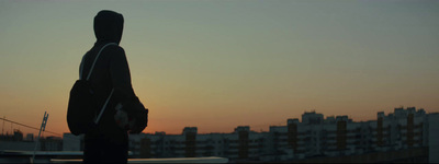 a person with a back pack standing in front of a sunset