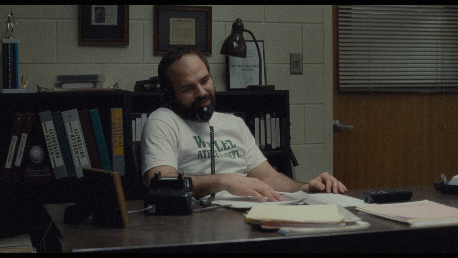 a man sitting at a desk in front of a book shelf