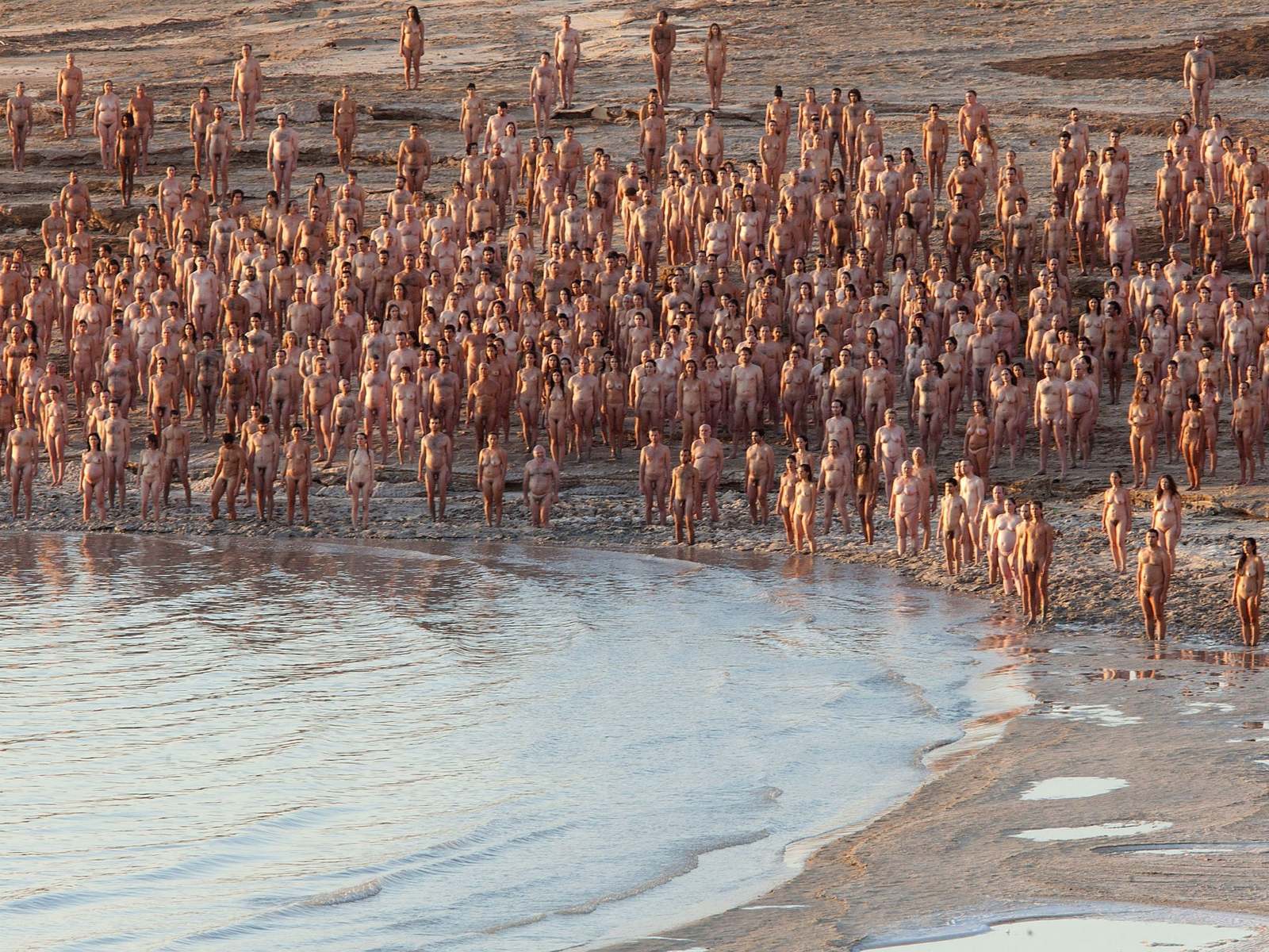 a large group of people standing next to a body of water