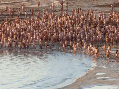 a large group of people standing next to a body of water