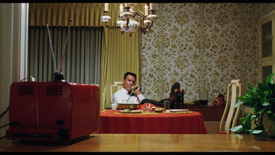 a man sitting at a table talking on a cell phone