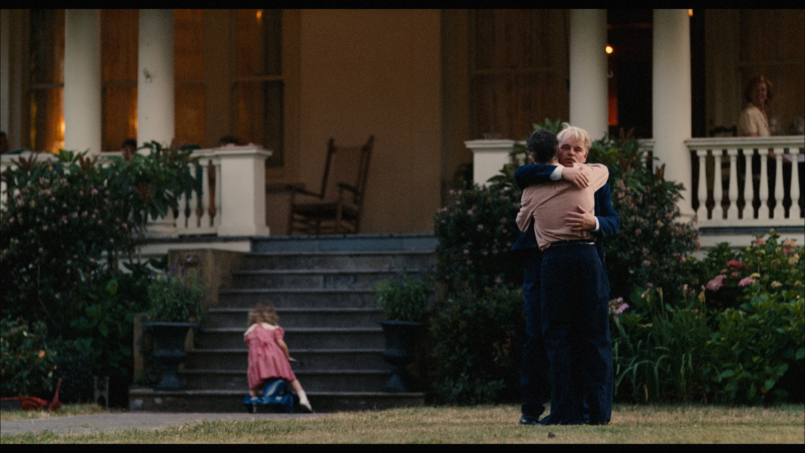 a man holding a child in front of a house