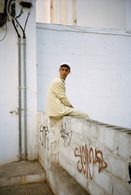 a man sitting on a wall with graffiti on it