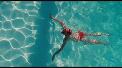 a man swimming in a pool with a frisbee