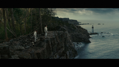 a couple of people standing on top of a cliff next to the ocean