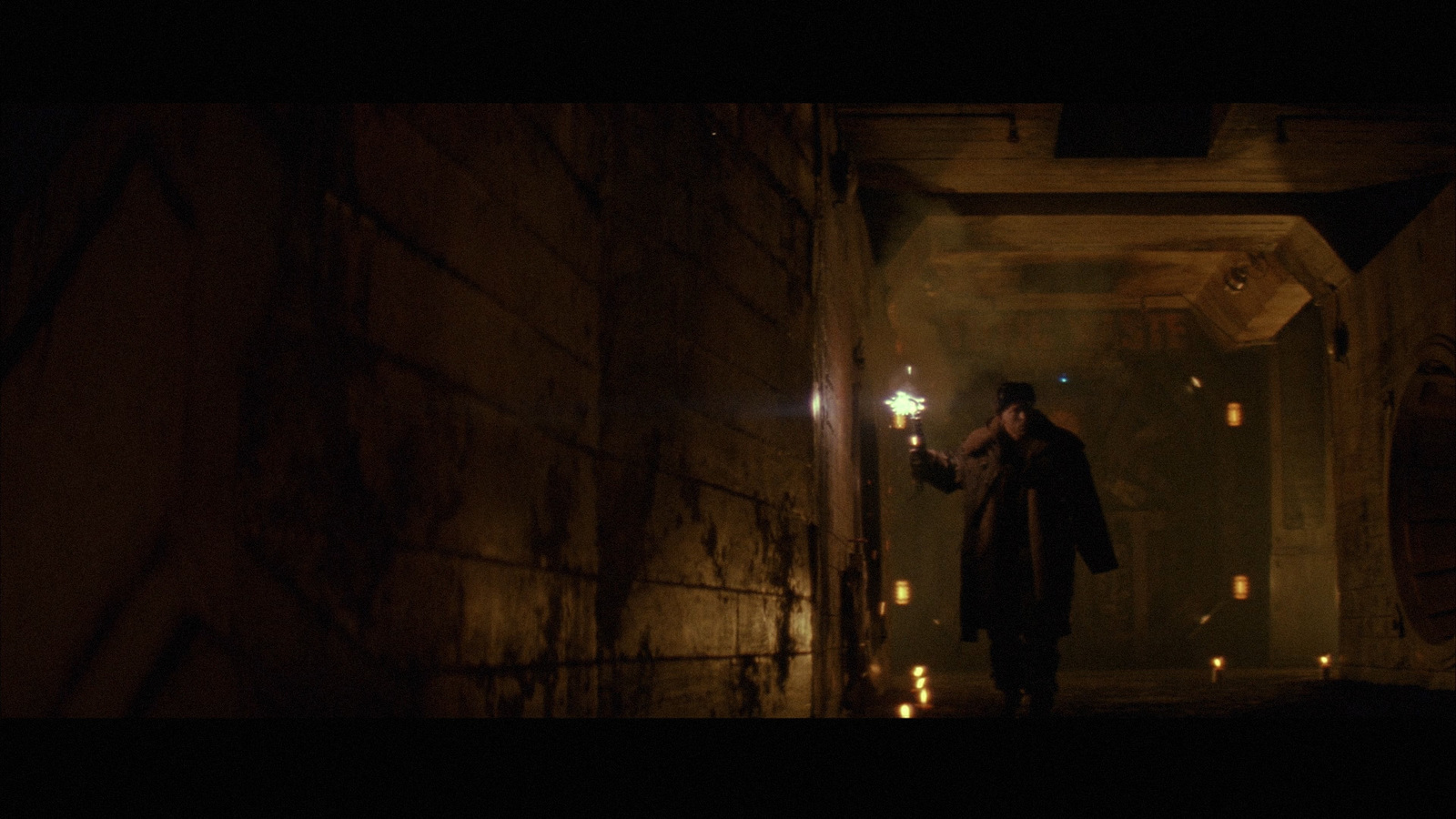 a man holding a flashlight in a dark alley