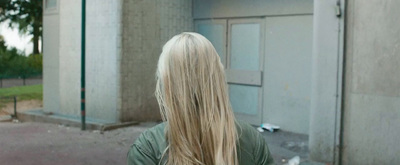 a woman with long blonde hair standing in front of a building