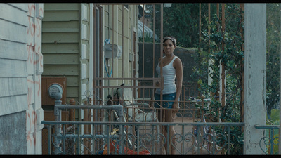 a woman standing on a balcony next to a building