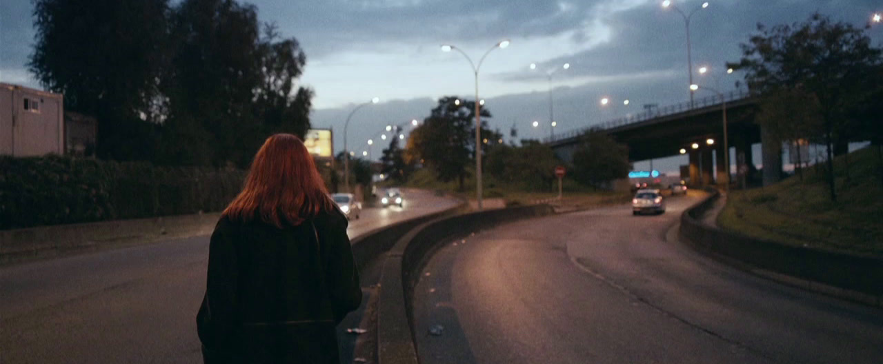 a woman standing on the side of a road at night